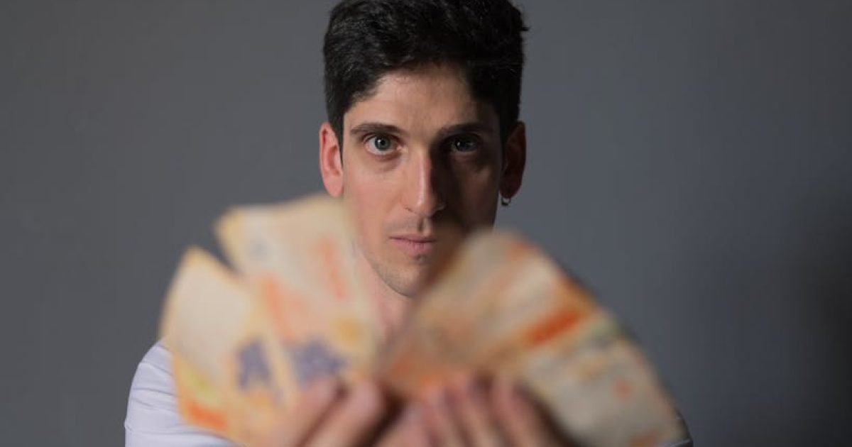 Retrato focado de um homem segurando notas de peso argentino, enfatizando conceitos financeiros.